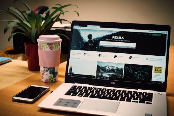 pexels photo 811587 A tidy desk setting with a laptop showing a stock photo website and a smartphone.